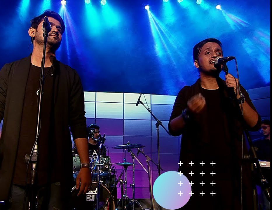 AR Divine singing on stage with a band under blue and purple stage lights