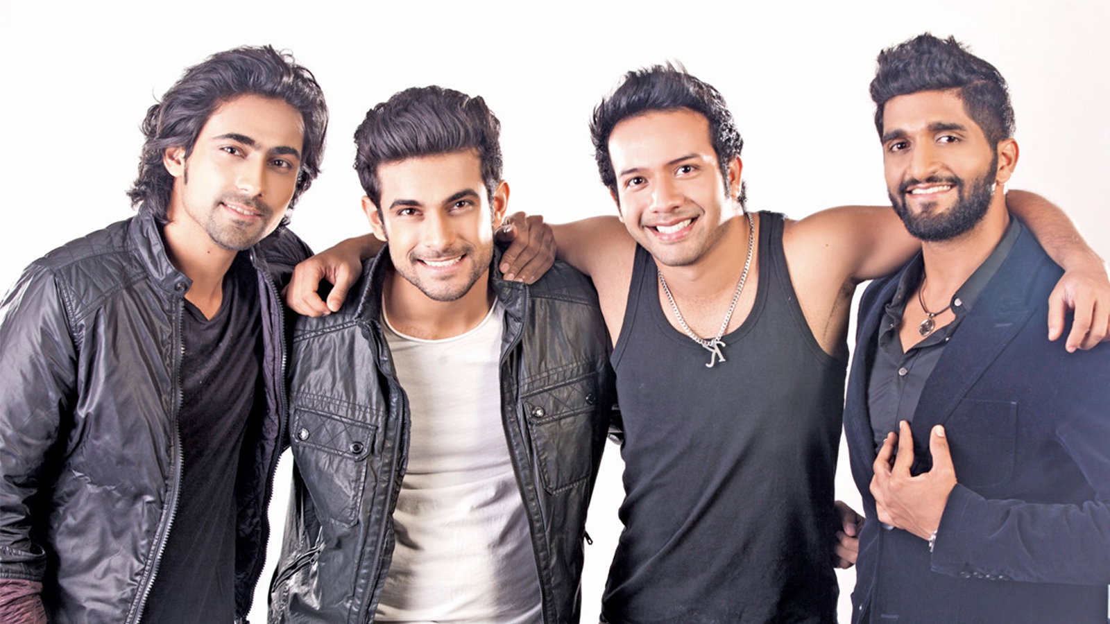 Sanam, stand with their arms around each other, smiling at the camera against a white background.
