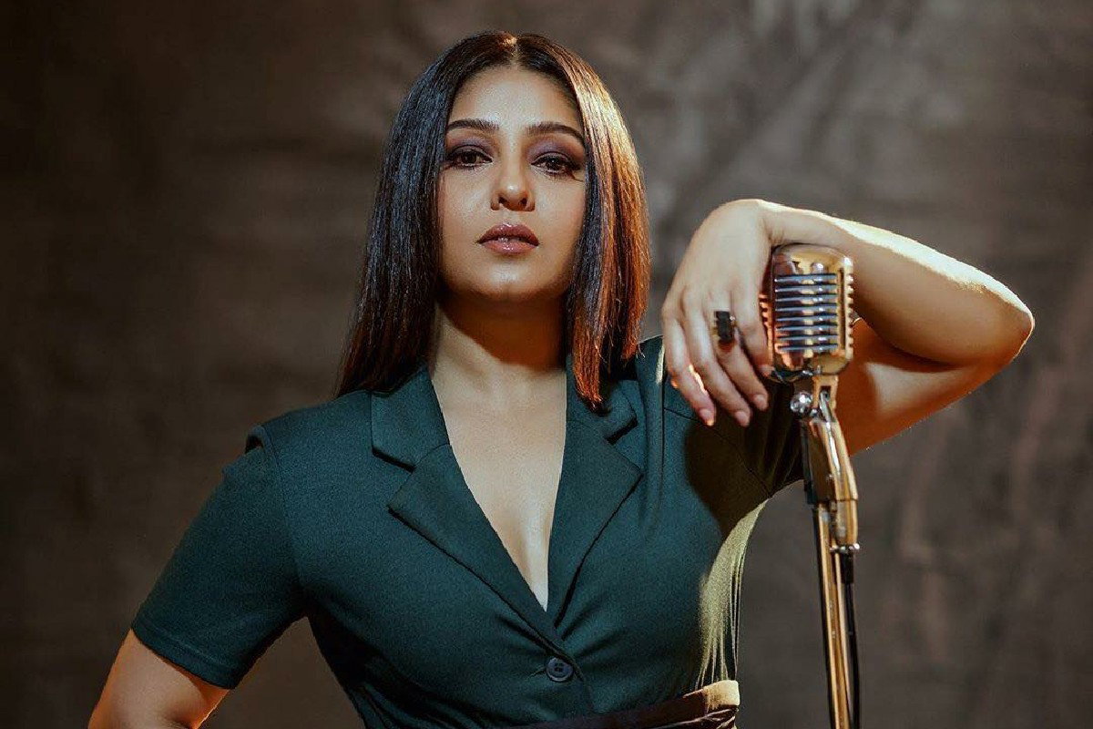 Sunidhi Chauhan standing with her arm on the mic, staring into the camera