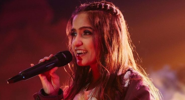 Asees Kaur performing on the stage and posing for the image.